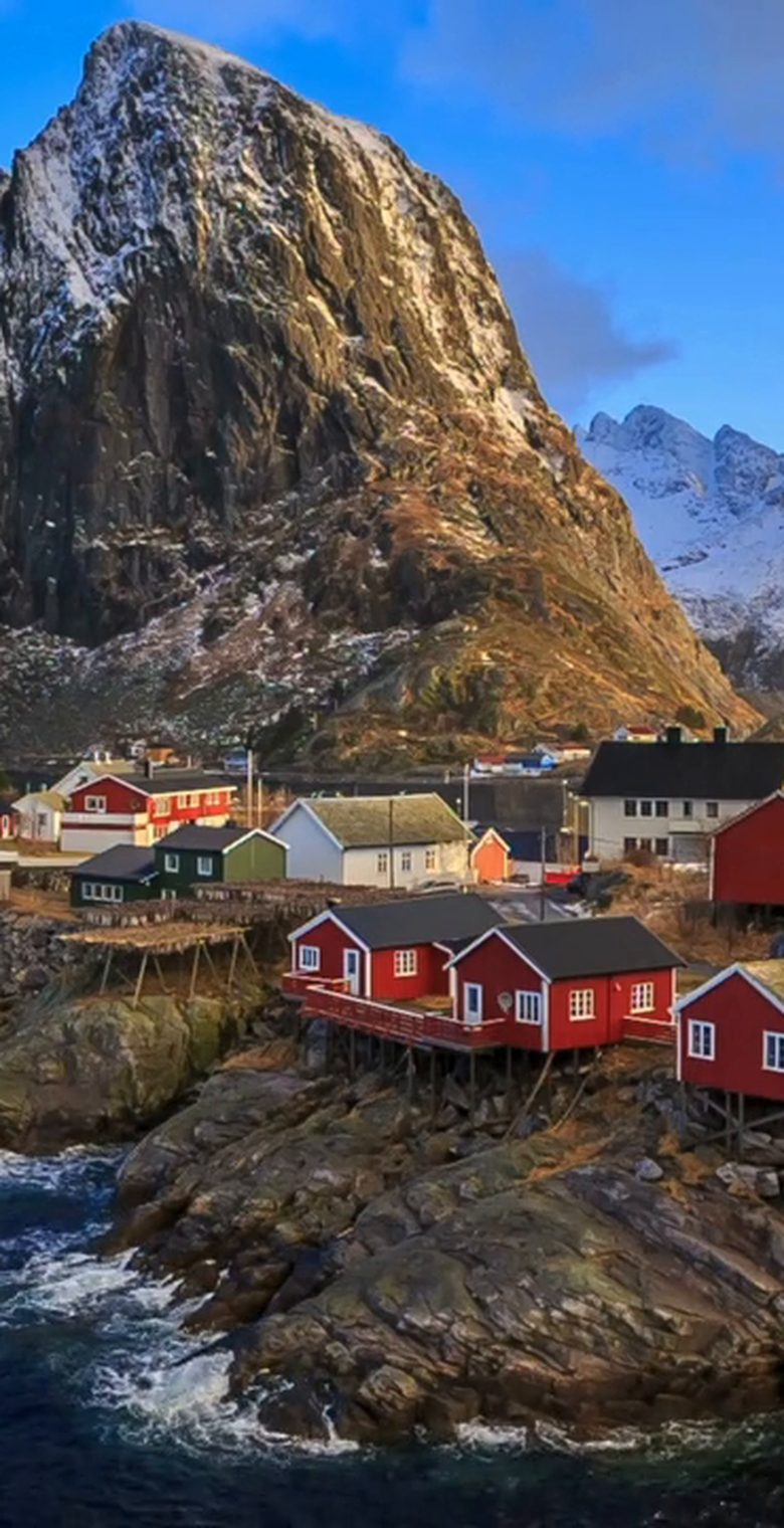 Red fishing cabins below a mountain peak in the Lofoten Islands
